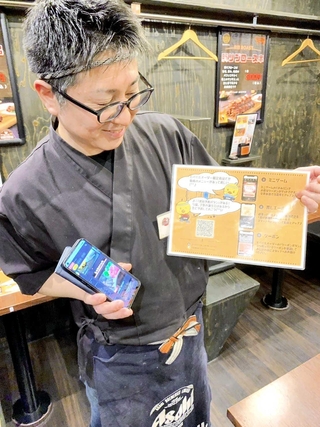 ＬＩＮＥを使ったセルフオーダーを導入した店舗で、ミニゲームやクーポンなどを取得できるシステムを説明する疋田修三さん＝姫路市田寺３、喜鳥家田寺店
