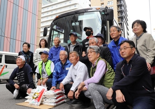 被災者に贈る米を前に、出発の記念撮影に臨むボランティアら＝神戸市中央区小野柄通