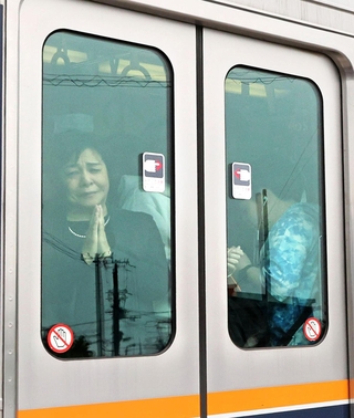 事故発生時刻近くに現場付近を通過する列車で手を合わせる乗客＝２５日午前９時２５分、尼崎市内（代表撮影）