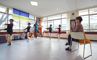 夫婦でバレエを指導するボグダンさん（奥中央）とヴィクトリアさん（右）。教室にはウクライナ国旗が掲げられている＝３日、神戸市中央区八幡通２