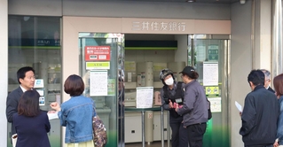 利用できなくなった三井住友銀行の出張所前で関係者の説明を受ける人ら＝２９日午後、神戸市中央区元町通１
