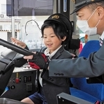 制服と帽子をかぶって、バスの運転席に座る子ども＝尼崎市東塚口町２