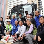 被災者に贈る米を前に、出発の記念撮影に臨むボランティアら＝神戸市中央区小野柄通