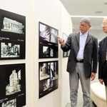 被災建物の写真と映像制作時の資料写真などが並ぶ企画展。内覧会で河田恵昭センター長（右）に三池敏夫さんが解説した＝人と防災未来センター