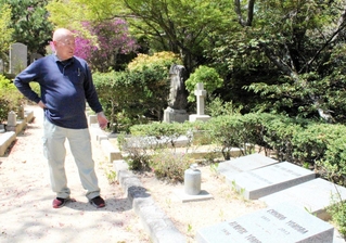 神戸で暮らしたドイツ人の捕虜らの墓碑の前に立つ榊原均さん＝神戸市北区山田町下谷上、神戸市立外国人墓地