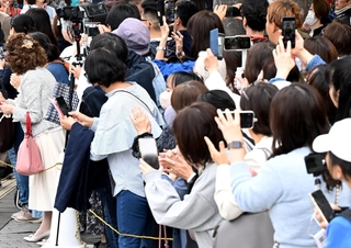 スマートフォンなどを手に街頭演説の会場に集まった有権者ら。ライブ中継をする人もいる＝２０２４年１０月、神戸市内