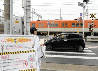 １月に２人が亡くなる事故があった踏切で注意を呼びかける警察官＝神戸市垂水区西舞子１