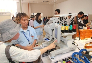 業務用の刺しゅう機でネームタグ作りを体験する来場者＝大阪市此花区の夢洲