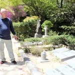 神戸で暮らしたドイツ人の捕虜らの墓碑の前に立つ榊原均さん＝神戸市北区山田町下谷上、神戸市立外国人墓地