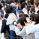 スマートフォンなどを手に街頭演説の会場に集まった有権者ら。ライブ中継をする人もいる＝２０２４年１０月、神戸市内