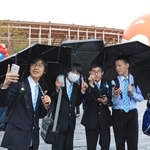 雨が降る中、傘を差して万博を楽しむ近畿大付属豊岡中の生徒たち＝大阪市此花区の夢洲