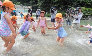 海に入って水をかけ合う園児たち＝６日午前、兵庫県新温泉町の諸寄・塩谷浜海水浴場