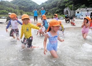 波打ち際で水遊びを楽しむ園児たち＝６日午前、兵庫県新温泉町の諸寄・塩谷浜海水浴場