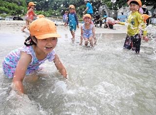 海に入って水をかけ合う園児たち＝６日午前、兵庫県新温泉町の諸寄・塩谷浜海水浴場