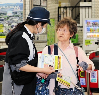 神戸電鉄岡場駅で利用者にビラを配る捜査員（左）＝６日午後、神戸市北区藤原台中町１