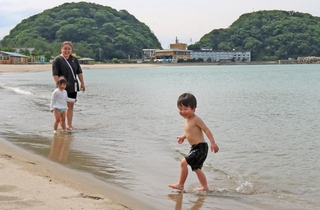 海辺で水遊びする親子連れ＝１６日午後、豊岡市竹野町竹野