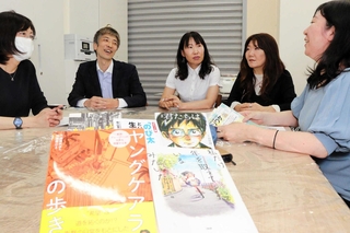 寄贈した本についてサポートステーション灘・つどいの家のスタッフから意見を聞く日本イーライリリーの川副祐樹さん（左から２人目）ら＝神戸市灘区永手町２