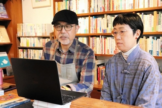 オンラインでつなぎ、沖縄戦戦没者の名前を読み上げる金澤伸昭さん（左）と由紀子さん＝神戸市東灘区岡本１、まめ書房、