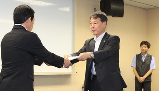 神戸市立中学で起きたいじめの再調査報告書を市教育委員会に手渡す松本隆行・再調査委員長（中央）＝神戸市中央区東川崎町１、市総合教育センター
