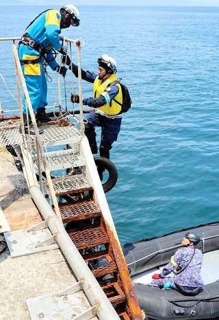 ゴムボートで桟橋に向かい、縄ばしごで上陸する兵庫県警の隊員＝洲本市由良町内田
