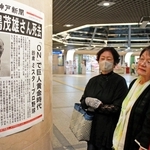 長嶋茂雄さんの死去を伝える号外を見る女性ら＝３日午前、神戸市中央区