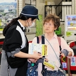 神戸電鉄岡場駅で利用者にビラを配る捜査員（左）＝６日午後、神戸市北区藤原台中町１