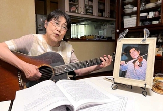 夫澄彦さんの写真を前にアスベストを題材にした歌を歌う平地千鶴子さん。生前は一緒に音楽を楽しんだという＝尼崎市