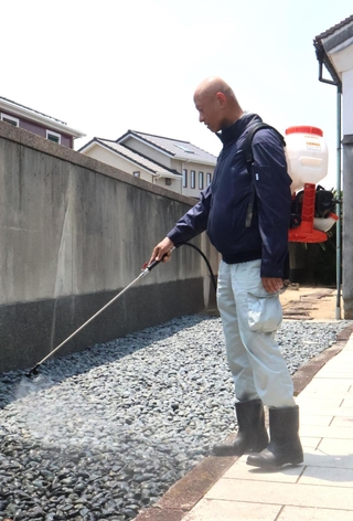 汚水があふれ出た住宅の庭で、消毒剤を散布する作業員＝明石市藤江