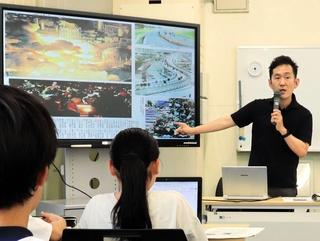 東日本大震災直後の紙面を見せながら語る男性記者＝姫路市立豊富小中学校