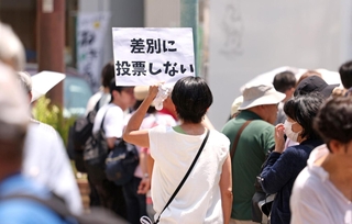 選挙戦は終盤に。自らの決意を込めて紙を掲げる女性＝神戸市中央区