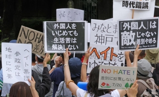 参政党の演説会場で、プラカードを掲げて抗議する人たち＝１７日、神戸市中央区加納町６、東遊園地
