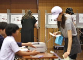選挙区の投票を済ませた後に、記載台で比例代表の投票先を書き入れる有権者ら＝２０日午前、神戸市中央区山本通１（撮影・長嶺麻子）