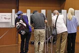 記載台で比例代表の投票先一覧を確認する有権者ら＝２０日午前、神戸市中央区山本通１（撮影・長嶺麻子）