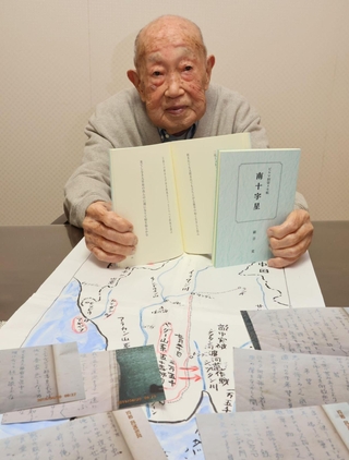 短歌を書いたメモ帳の写真を前に自費出版の短歌集を持つ細谷寛さん＝神戸市垂水区
