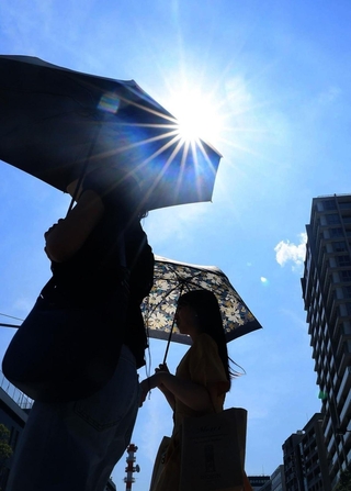 強い日差しが降り注ぎ、日傘を差す人の姿が目立った＝２９日午後、神戸市中央区海岸通１（撮影・笠原次郎）