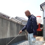 汚水があふれ出た住宅の庭で、消毒剤を散布する作業員＝明石市藤江