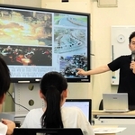 東日本大震災直後の紙面を見せながら語る男性記者＝姫路市立豊富小中学校