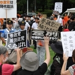 オレンジの服を着た参政党の陣営関係者に対し、プラカードを掲げて抗議する人たち。やじを飛ばす人もおり、双方の間にトラブルを警戒する警察官が立っていた＝17日午後、神戸市中央区加納町６、東遊園地