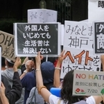 参政党の演説会場で、プラカードを掲げて抗議する人たち＝１７日、神戸市中央区加納町６、東遊園地