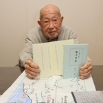 短歌を書いたメモ帳の写真を前に自費出版の短歌集を持つ細谷寛さん＝神戸市垂水区