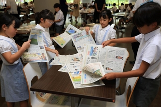 会場で新聞を手に取り、興味がある記事を探す児童たち＝１日午前、神戸市東灘区岡本８、甲南大学岡本キャンパス（撮影・笠原次郎）