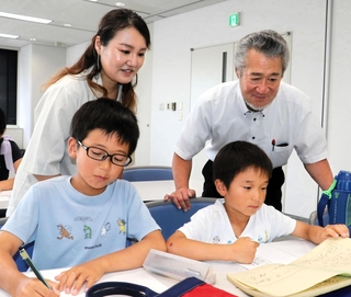 感想文を書く児童を見守る米山正幸さん（後列右）と未来さん（同左）＝神戸市中央区東川崎町１、神戸新聞社