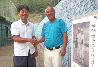 父馨さんらの顕彰碑の前で、東洋大姫路の岡田龍生監督（右）を激励する野球部ＯＢ会長の梅谷真吾さん＝姫路市打越の同校グラウンド（撮影・辰巳直之）