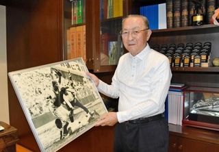 甲子園の審判時代の写真を手に思い出を語る三輪武さん＝神戸市灘区
