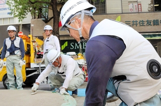 背中に２カ所のファンを取り付けた空調ベストを着て、作業する神戸市建設局中部建設事務所の職員。中に保冷剤を入れるポケットもあり、より冷気を感じながら仕事に集中できるという＝神戸市中央区三宮町１