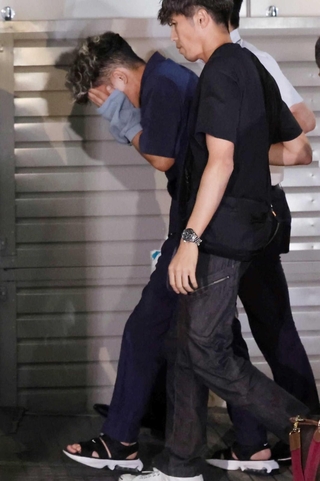捜査員に付き添われ、葺合署に入る谷本将志容疑者＝２２日午後１１時４２分、神戸市中央区吾妻通５