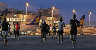 まだ夜の明けきらない中、駐機する飛行機の前を走り抜けるランナーたち＝３０日朝、神戸市中央区、神戸空港