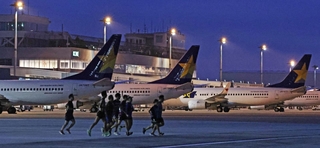 まだ夜の明けきらない中、駐機する飛行機の前を走り抜けるランナーたち＝３０日朝、神戸市中央区、神戸空港