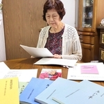 夫格知さんが残した手記を読む高橋一枝さん。手前は父横山復次さんの手記が収められていた「忘れな草」の冊子＝明石市明南町２