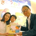 １万人目の来場者となり、記念に絵本２冊を受け取った太田三恵さん（左）と暖士君＝神戸ファッション美術館